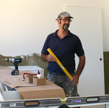 A builder at work on-site with tools including spirit level and drill.